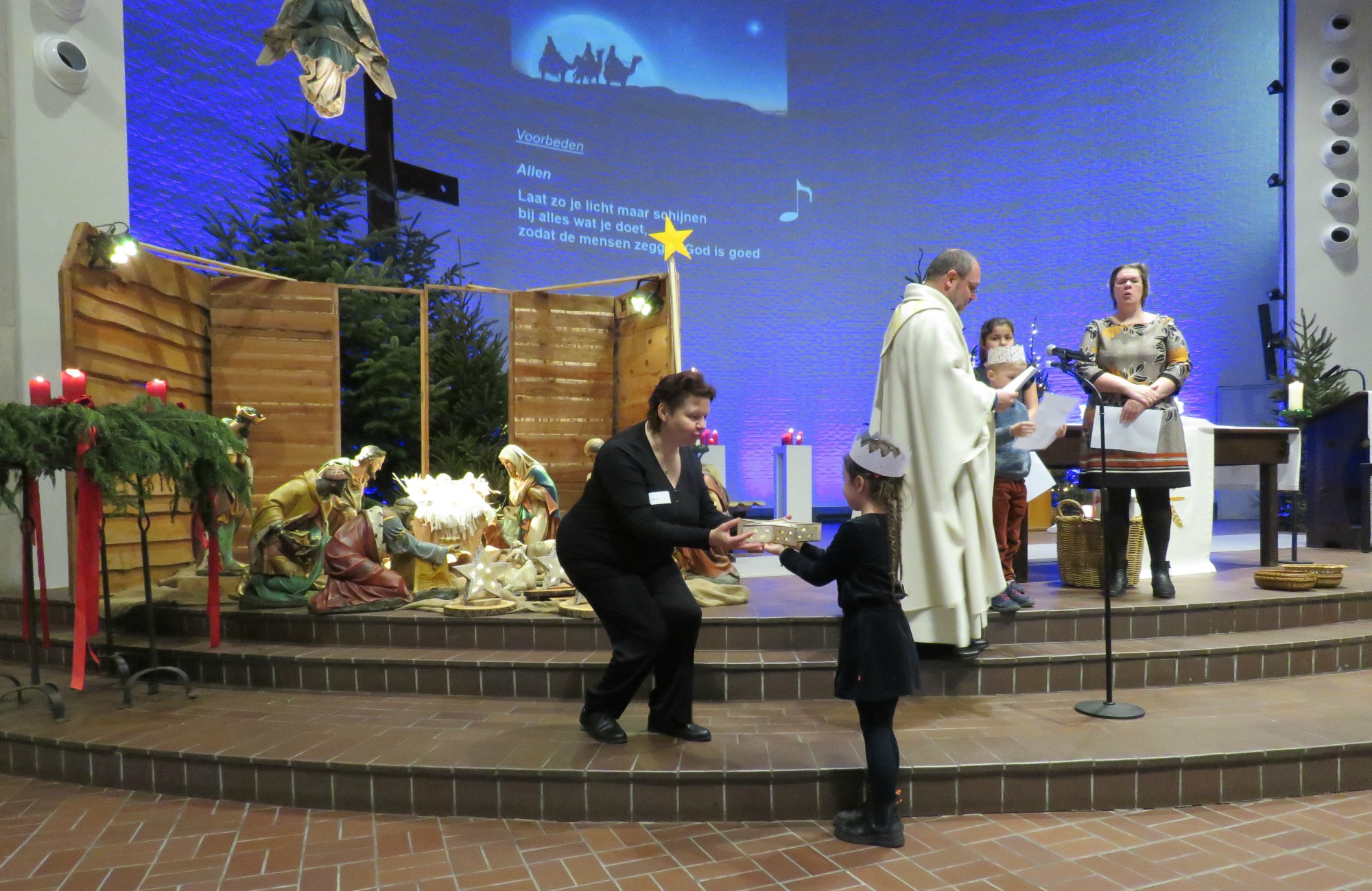 Aanbrengen van sterren bij de kerststal door de eerste communicanten